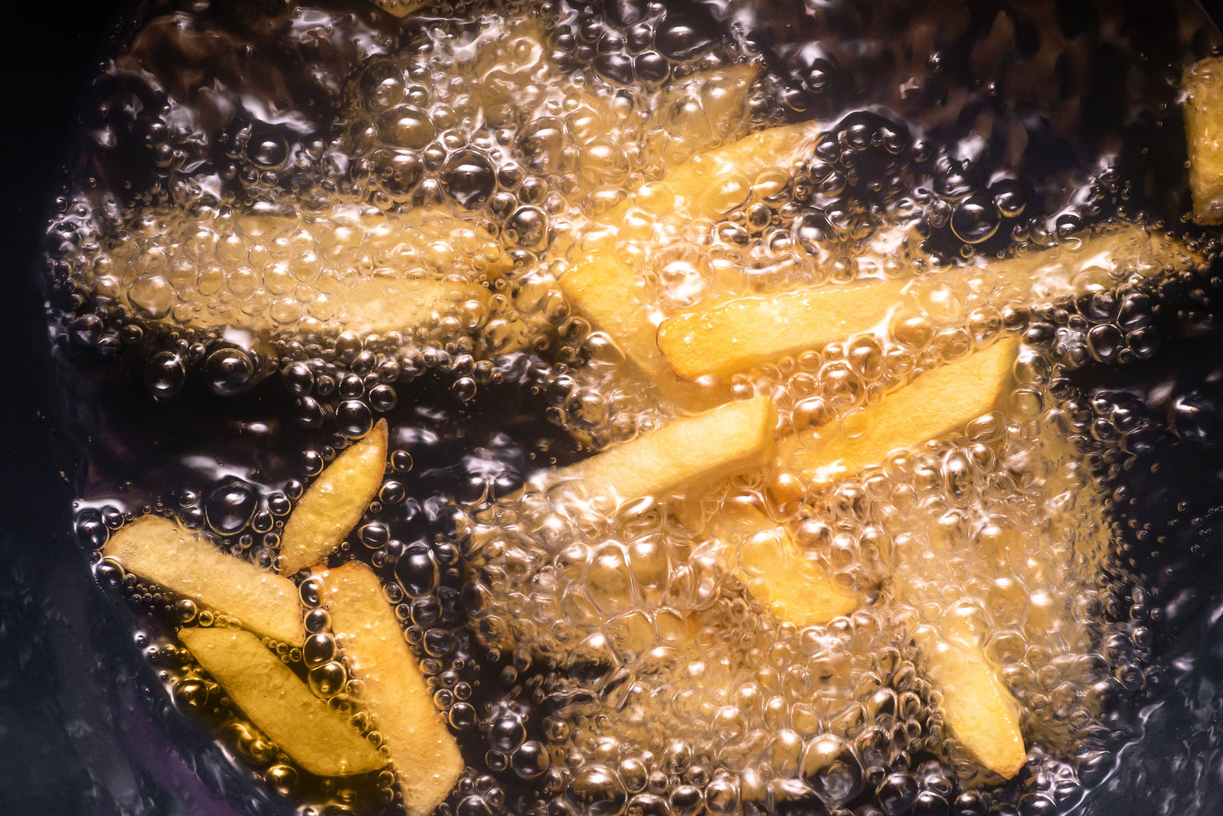 Pommes frites werden in heissem Öl frittiert *** French fries are deep fried in hot oil 1028901606