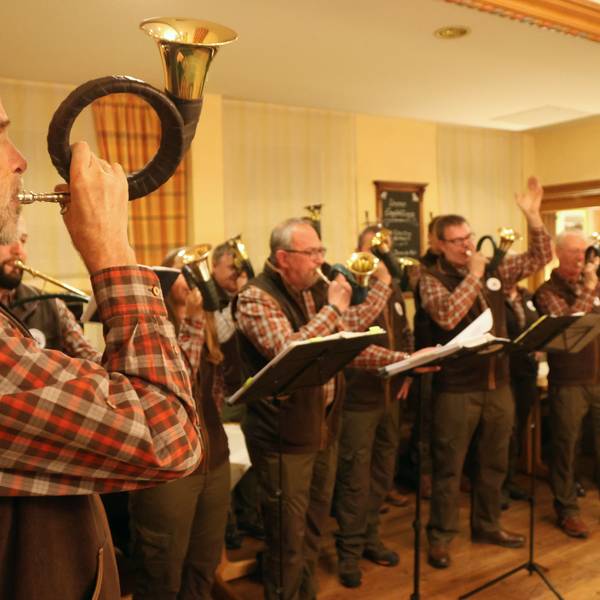 Ein Gruppe von Jagdhornbläsern folgt dem Signal ihres Leiters.