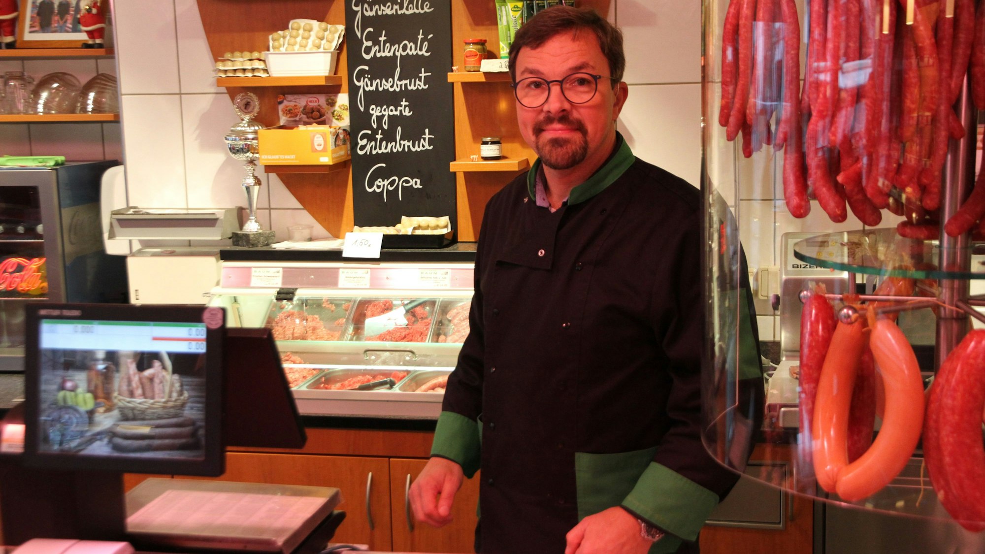 Ein Fleischermeister hinter der Theke seiner Metzgerei