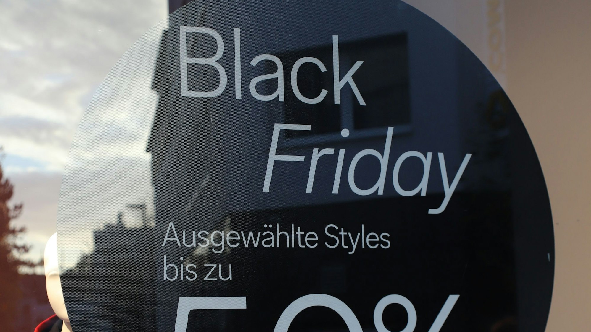 Blick in ein Schaufenster in Siegburg, auf dem ein Schild 50-Prozent-Rabatte ausweist.