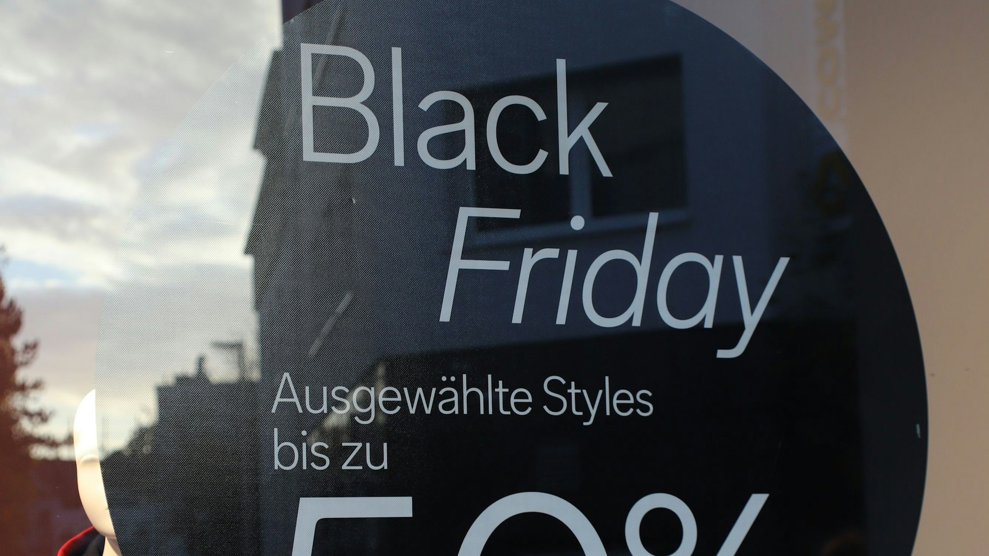 Blick in ein Schaufenster in Siegburg, auf dem ein Schild 50-Prozent-Rabatte ausweist.