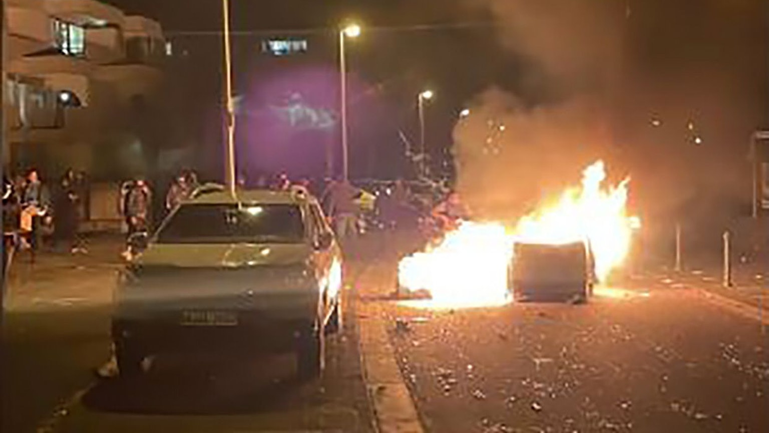 Auf einer Straße brennt eine Mülltonne.