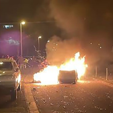 Auf einer Straße brennt eine Mülltonne.