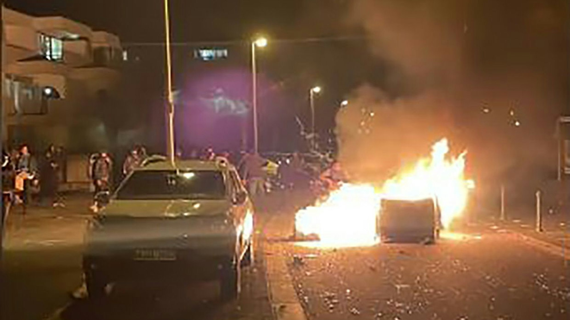 Auf einer Straße brennt eine Mülltonne.