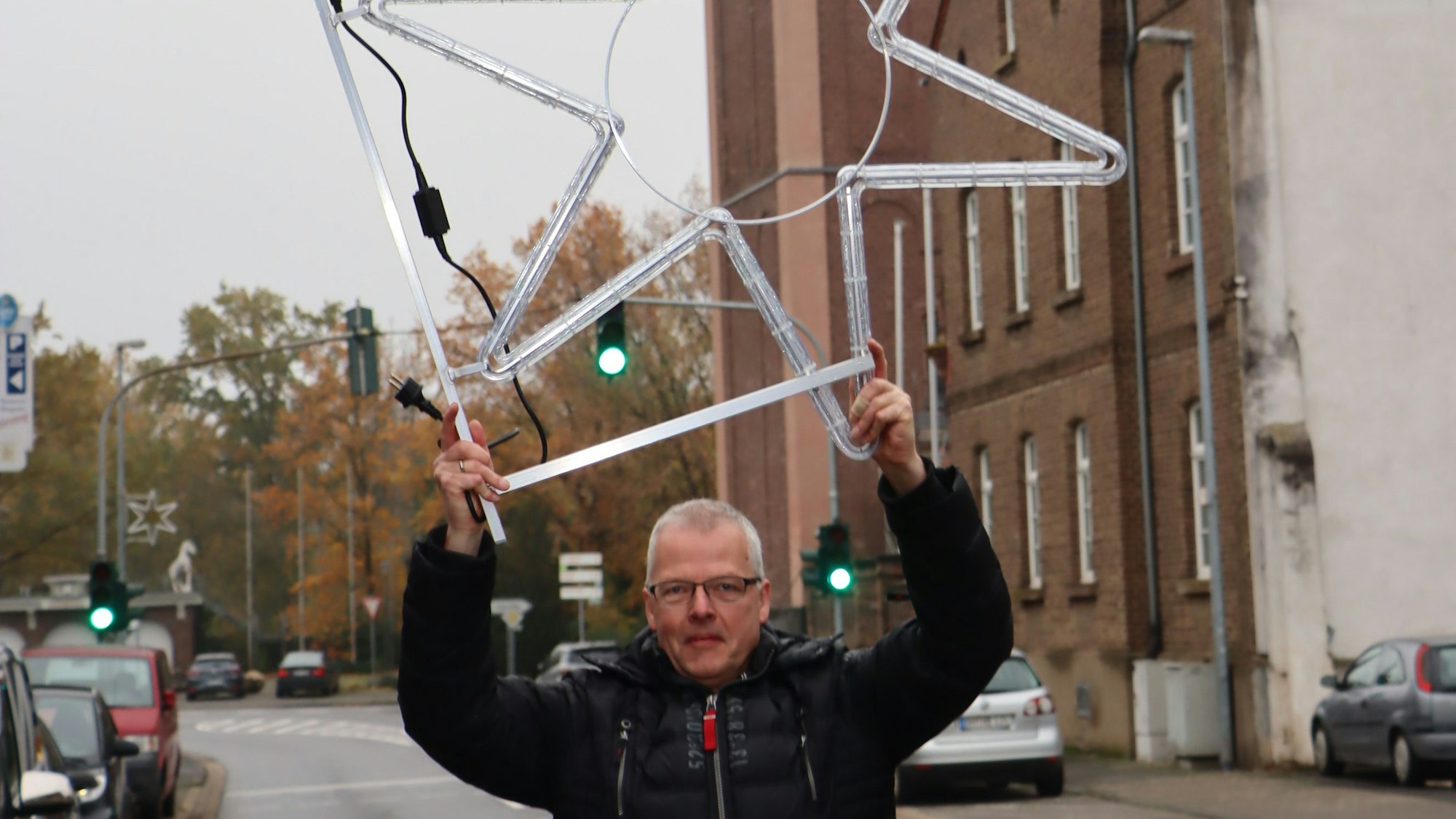 Ein Mann hält einen Weihnachtsstern hoch, er gehört zur Weihnachtsbeleuchtung in Erftstadt-Gymnich.