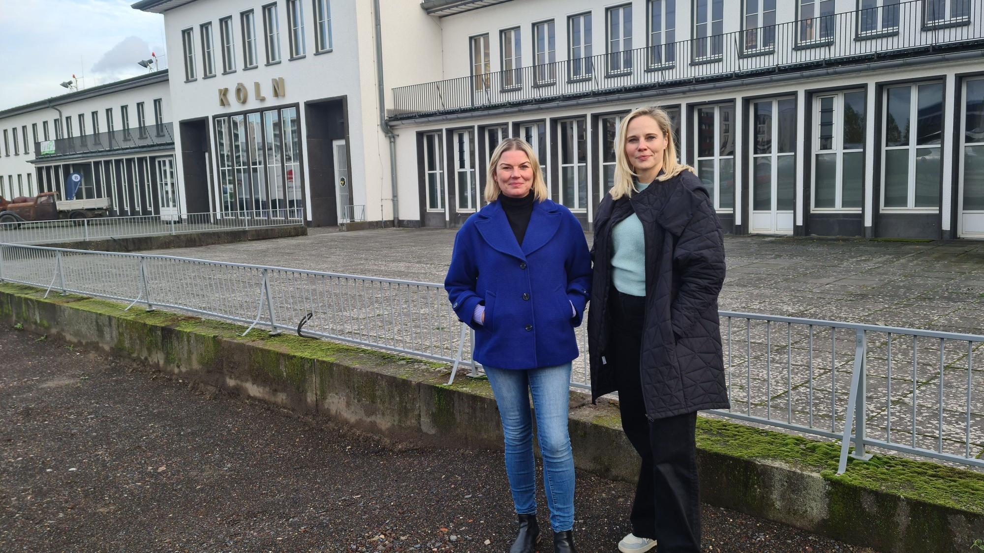 Zwei Frauen stehen vor der historischen Halle des Flughafens Butzweiler Hof.
