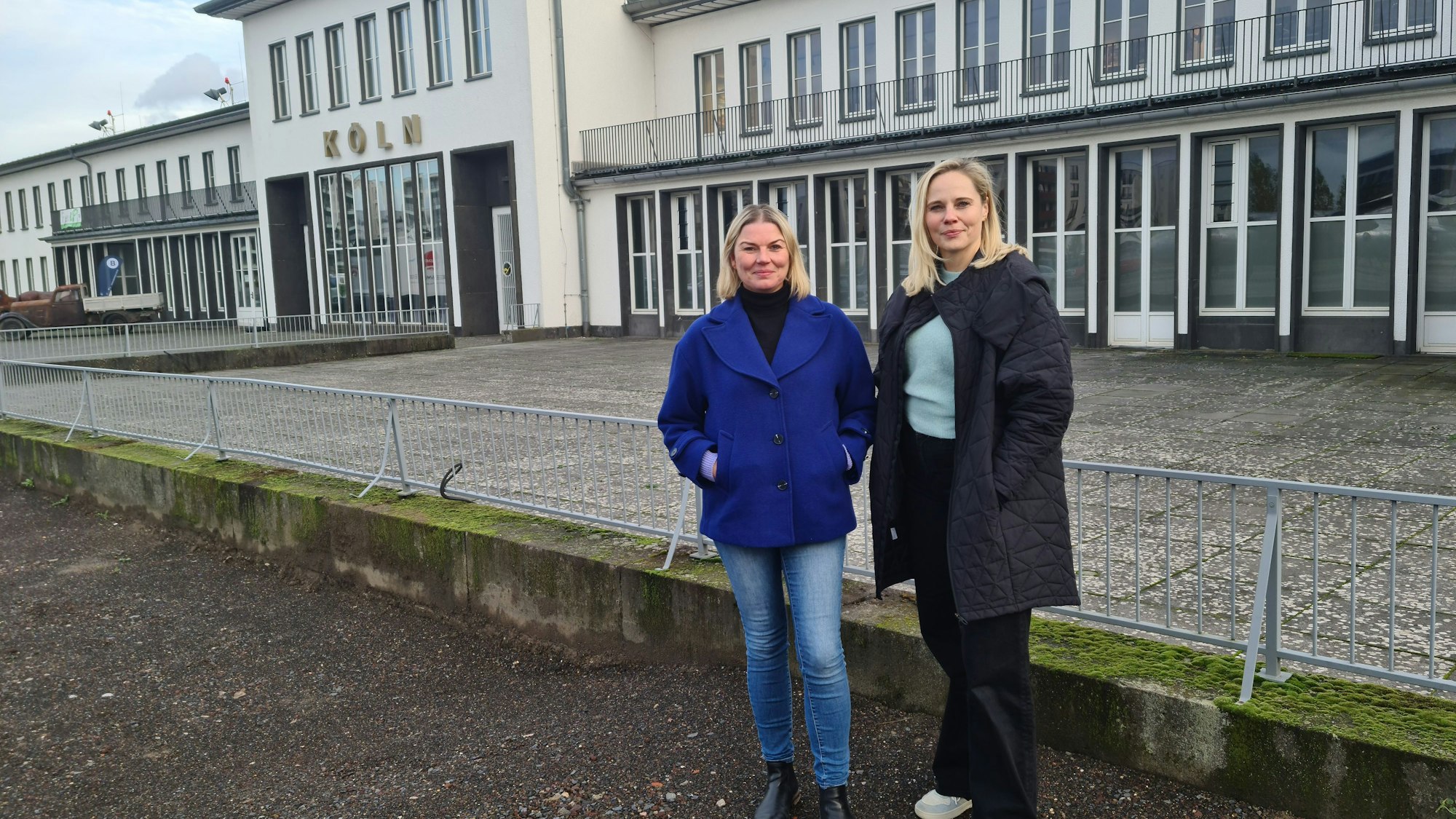 Zwei Frauen stehen vor der historischen Halle des Flughafens Butzweiler Hof.