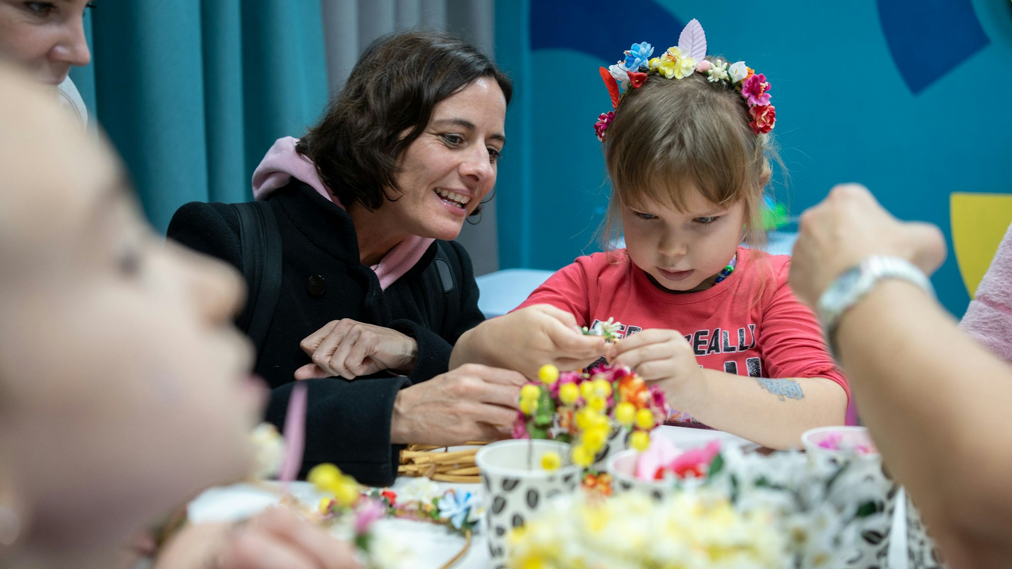 Ein kleines Mädchen bastelt einen Haarreifen mit Blumen.