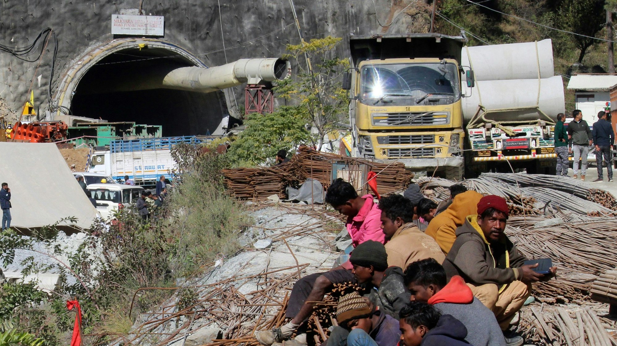 Menschen sitzen vor dem Eingang eines im Bau befindlichen Tunnels, der indischen Bundesstaat Uttarakhand eingestürzt ist.