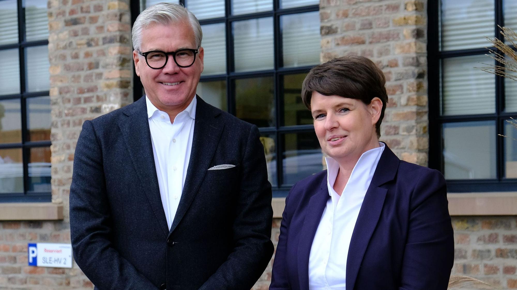 Johannes Molderings und Stephanie Forstner stehen im Außenbereich vor einem backstein-Gebäude.