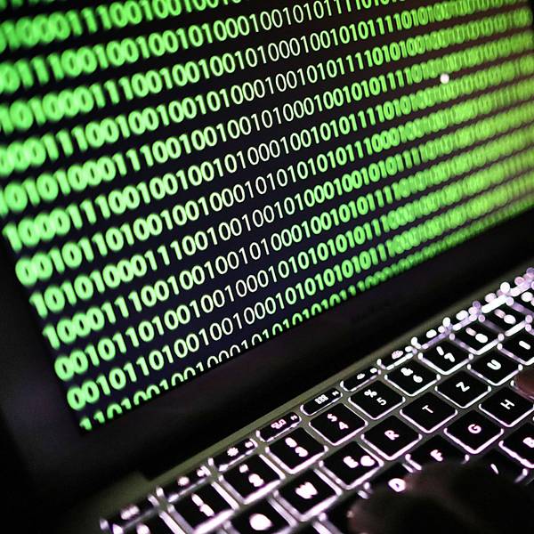 Auf dem Bildschirm eines Laptops ist ein Binärcode zu sehen.