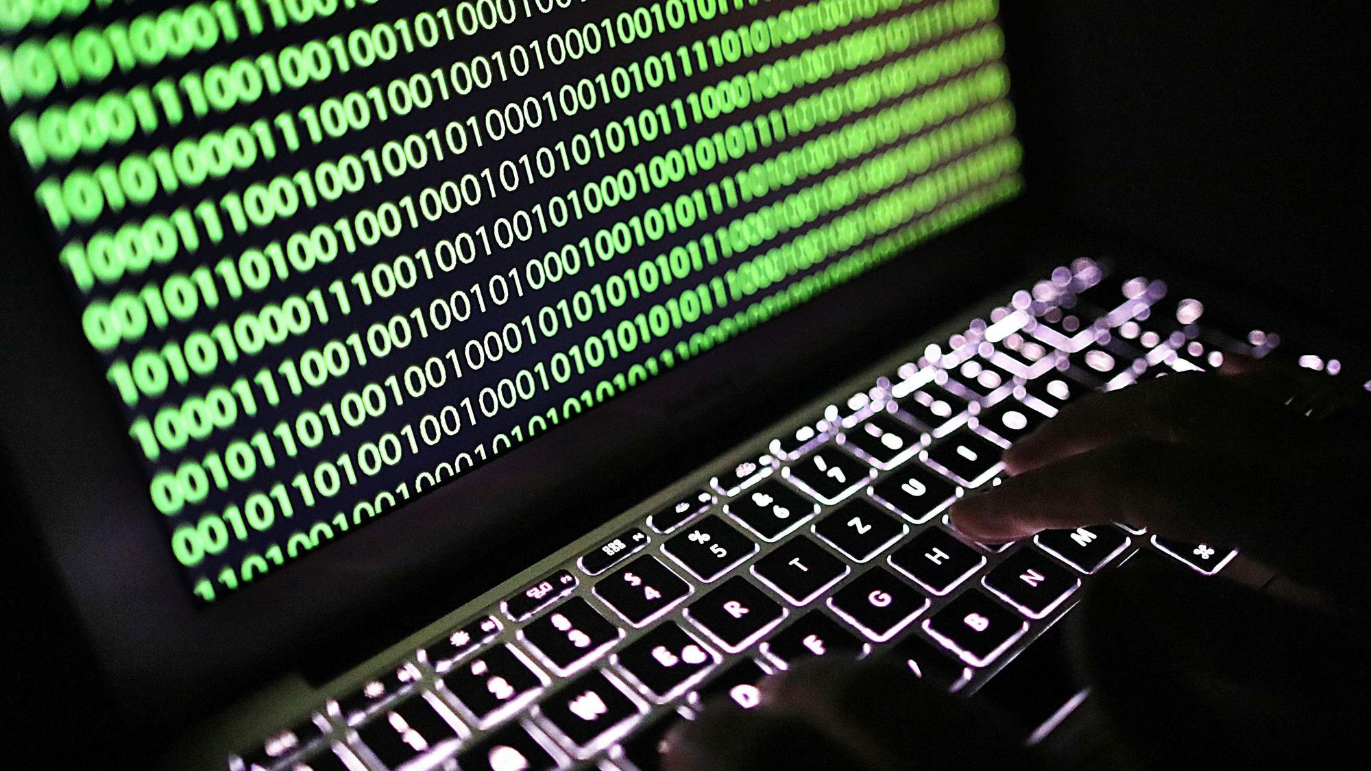Auf dem Bildschirm eines Laptops ist ein Binärcode zu sehen.