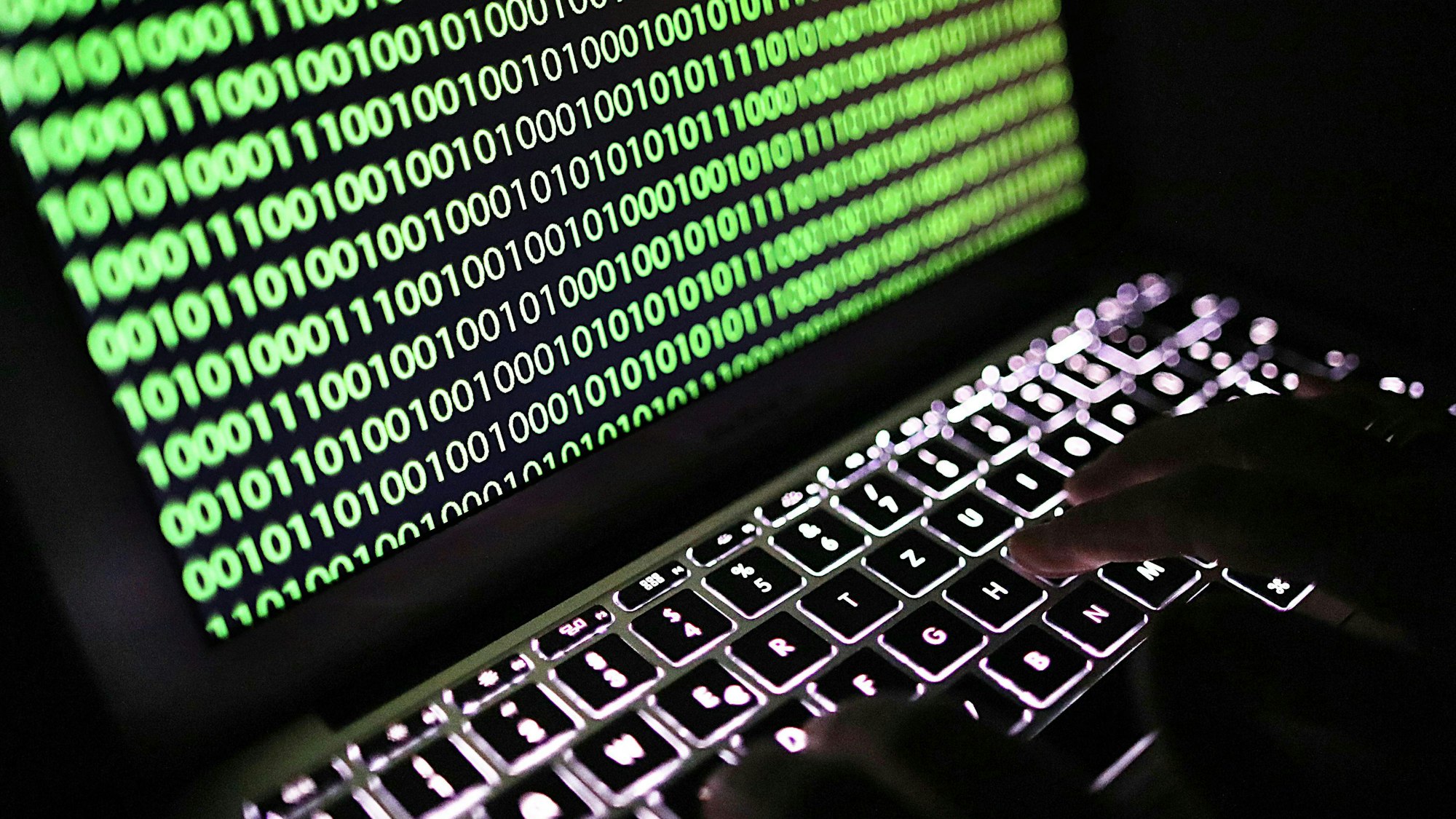 Auf dem Bildschirm eines Laptops ist ein Binärcode zu sehen.