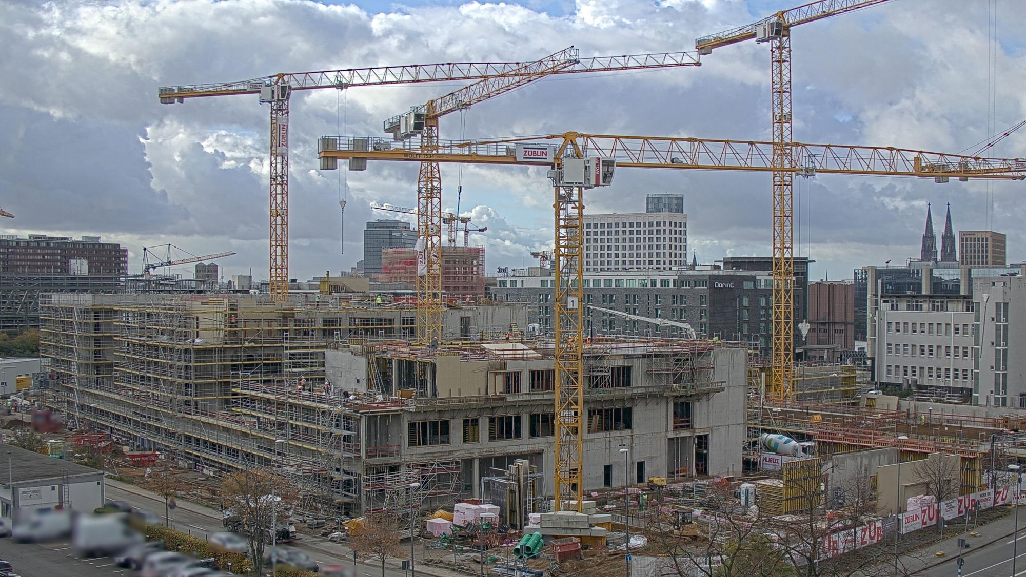 An den Gelenkbogenhallen 1 baut die Firma Züblin das neue Gymnasium für Deutz. Dahinter sind im linken Bildrand die Gleise und das Stadthaus zu sehen. Rechts die Messe und die Spitzen des Kölner Doms.