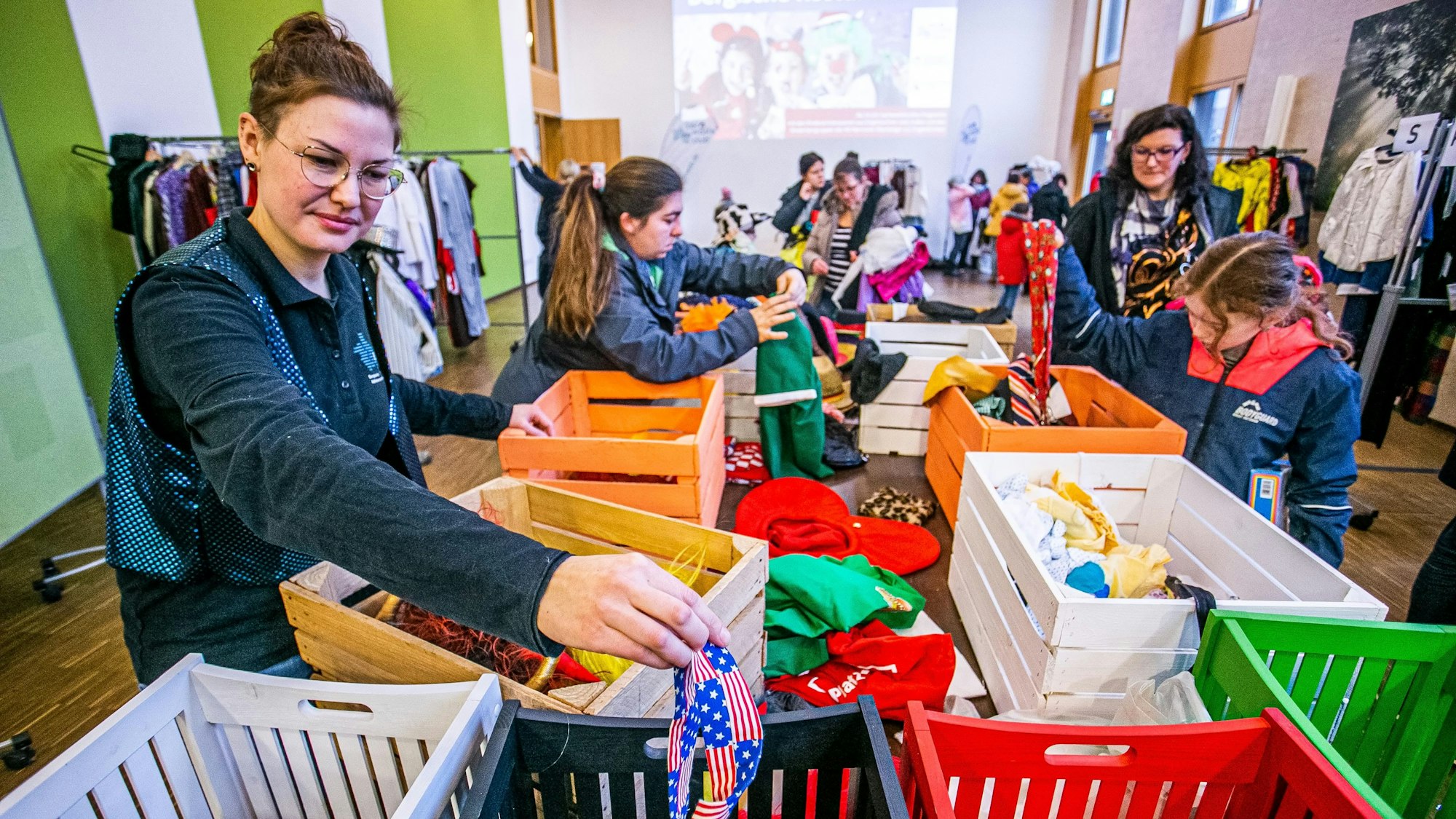 Eine Frau sortiert Karnevalskostüme in unterschiedliche Kisten.