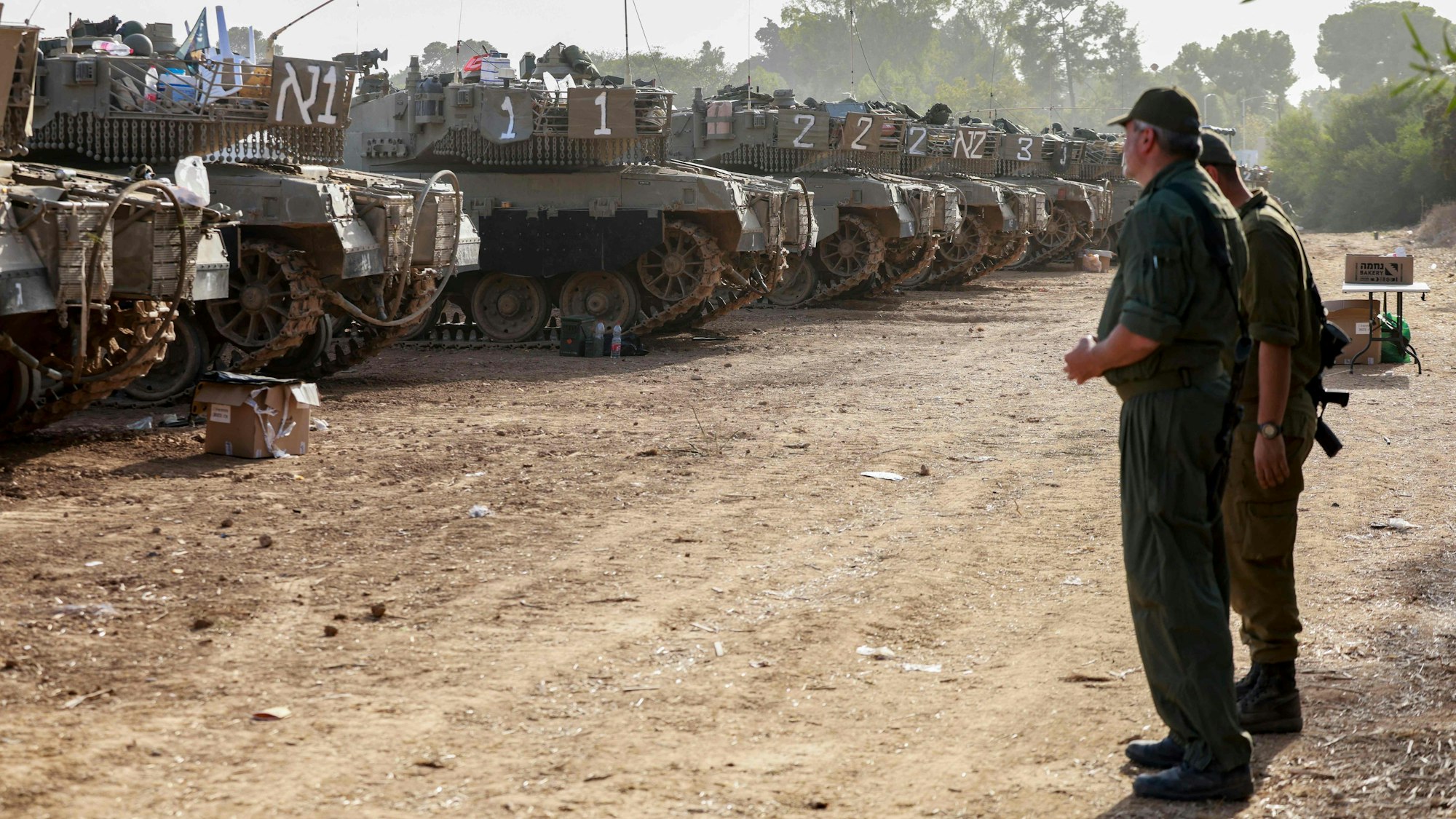 Israelische Soldaten stehen vor einer Reihe Panzer. Ein
