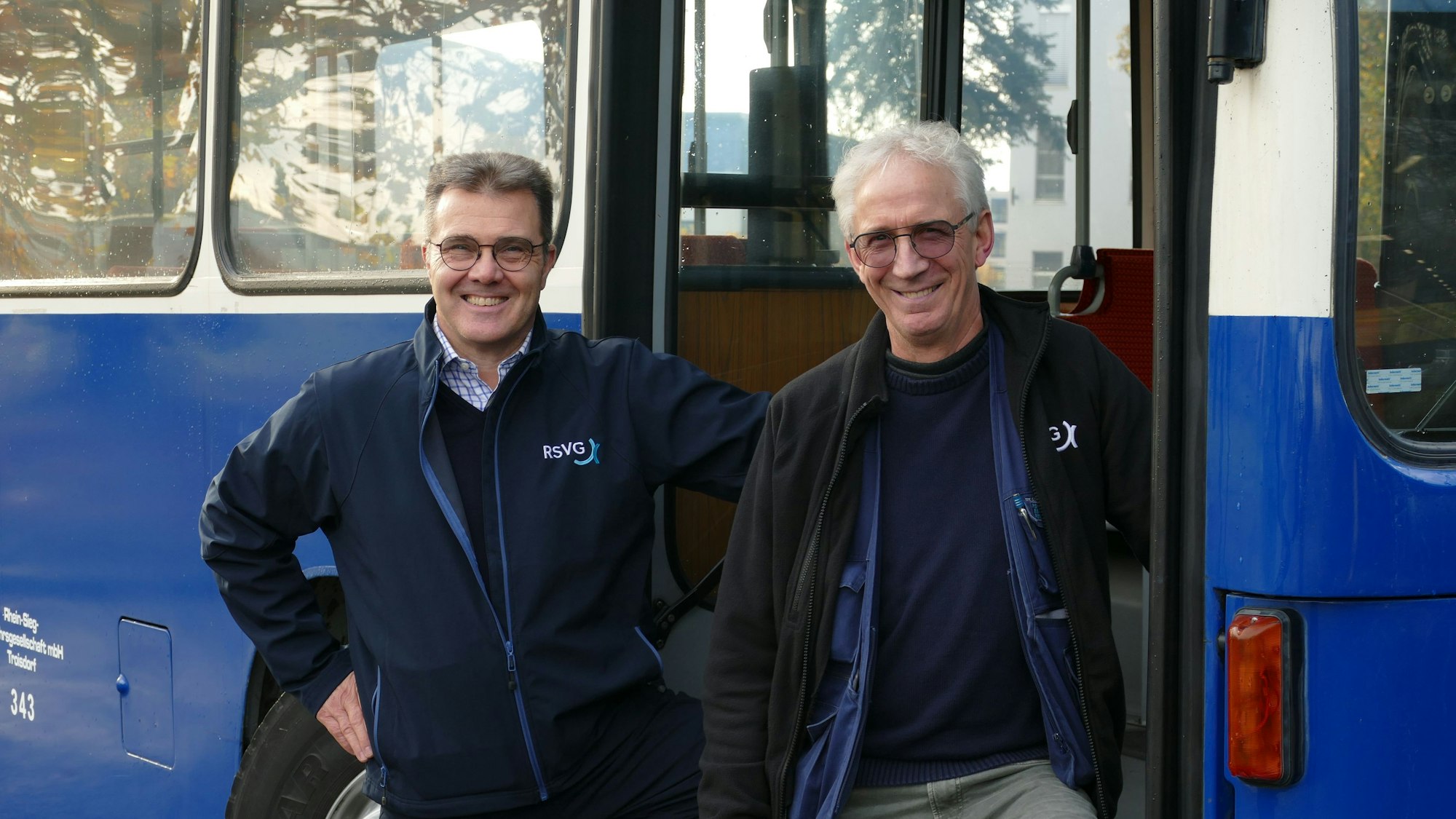 Zwei Männer stehen vor einem historsichen Bus.