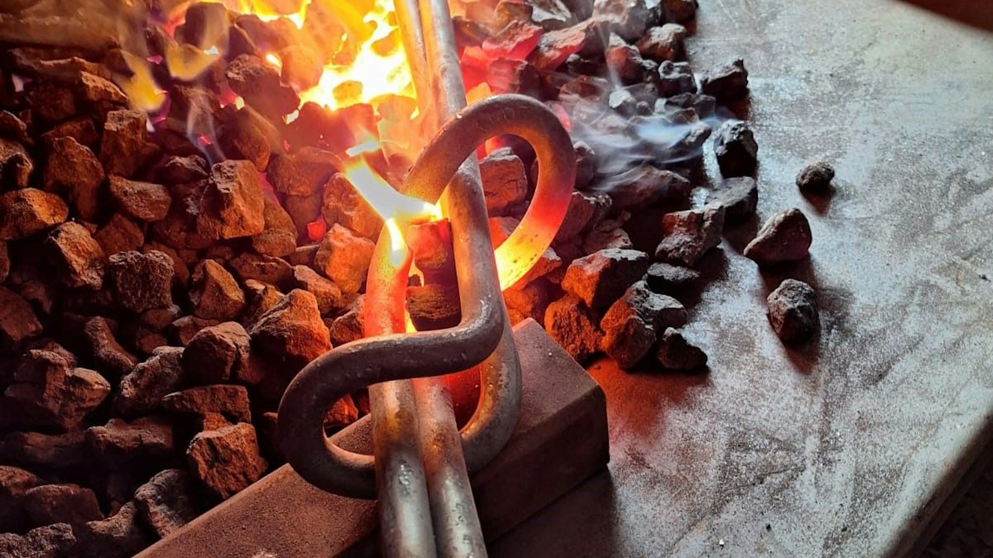 Zwei Stahlstangen werden in einem Schmiedefeuer erhitzt.