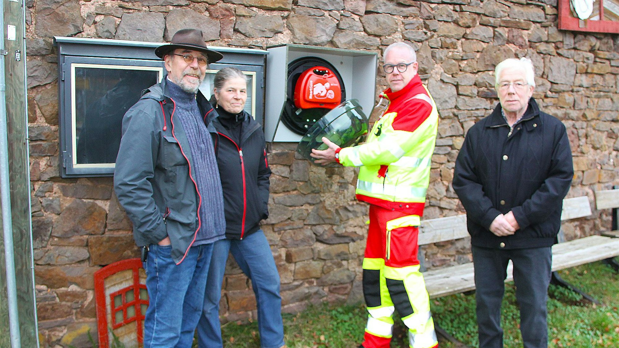 Reinhard und Marion Cremer, Notarzt Dr. Thomas Bons und Ortsvorsteher Robert Baales stehen vor dem Gerät.