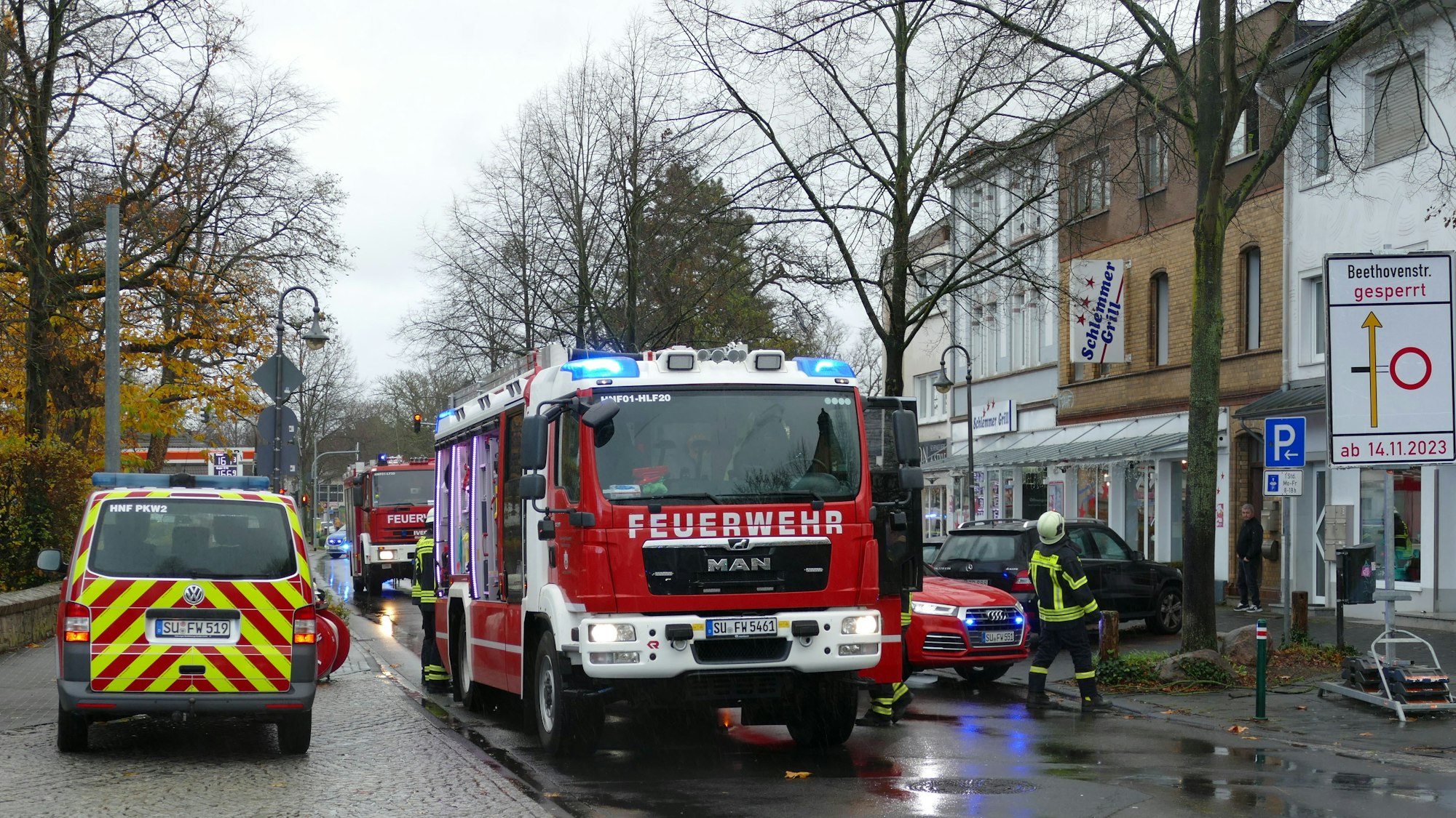 Feuerwehrleute stehen vor einem Brandhaus.