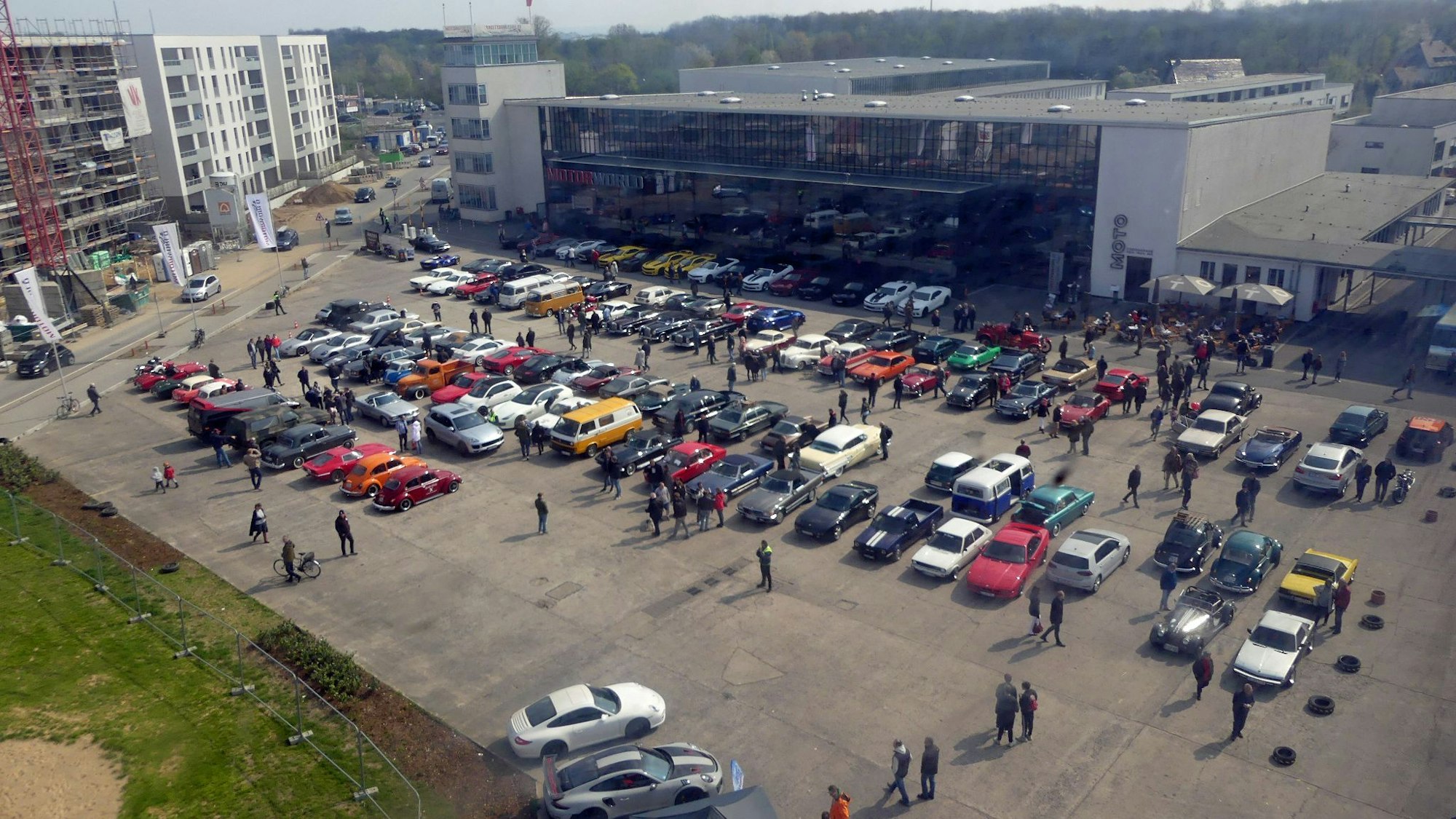 Auf einem Parkplatz stehen einige Autos vor einem großen zweistöckigen Gebäude.
