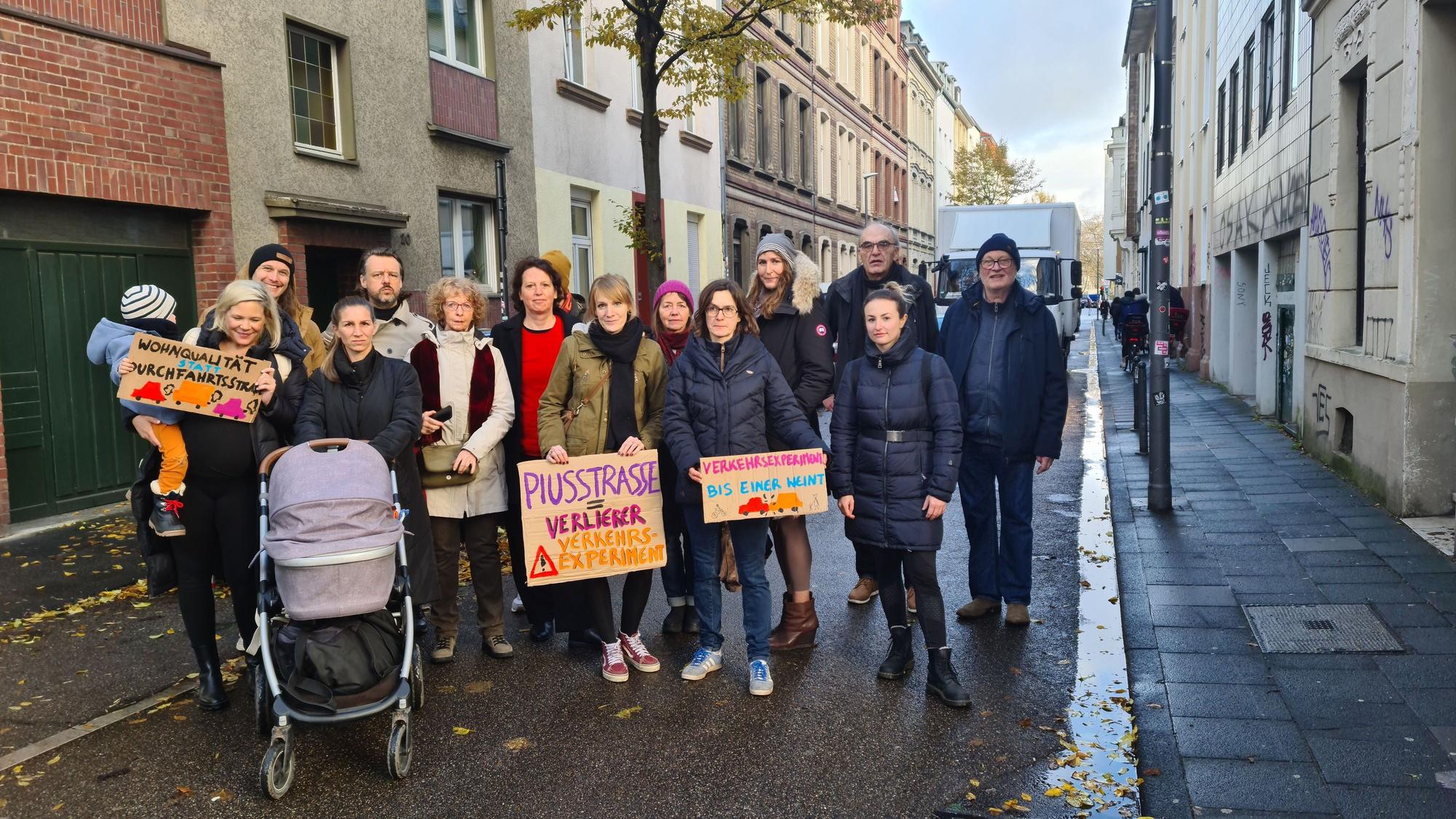 Eine Menschengruppe steht auf der Fahrbahn, einige alten Pappschilder hoch.