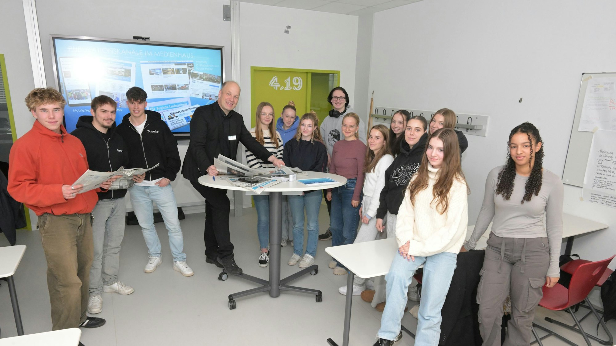 Schüler stehen mit Zeitungen in der Hand um einen Tisch.