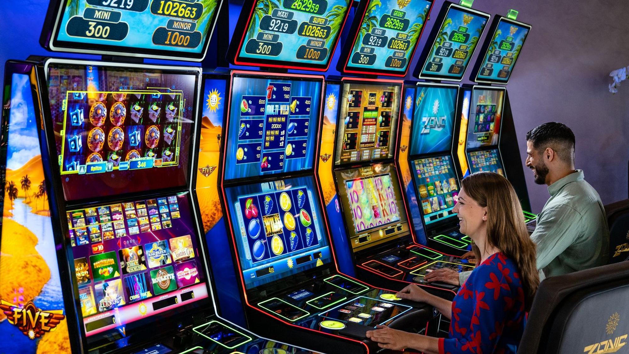 Eine Frau und ein Mann spielen an Glücksspielautomaten