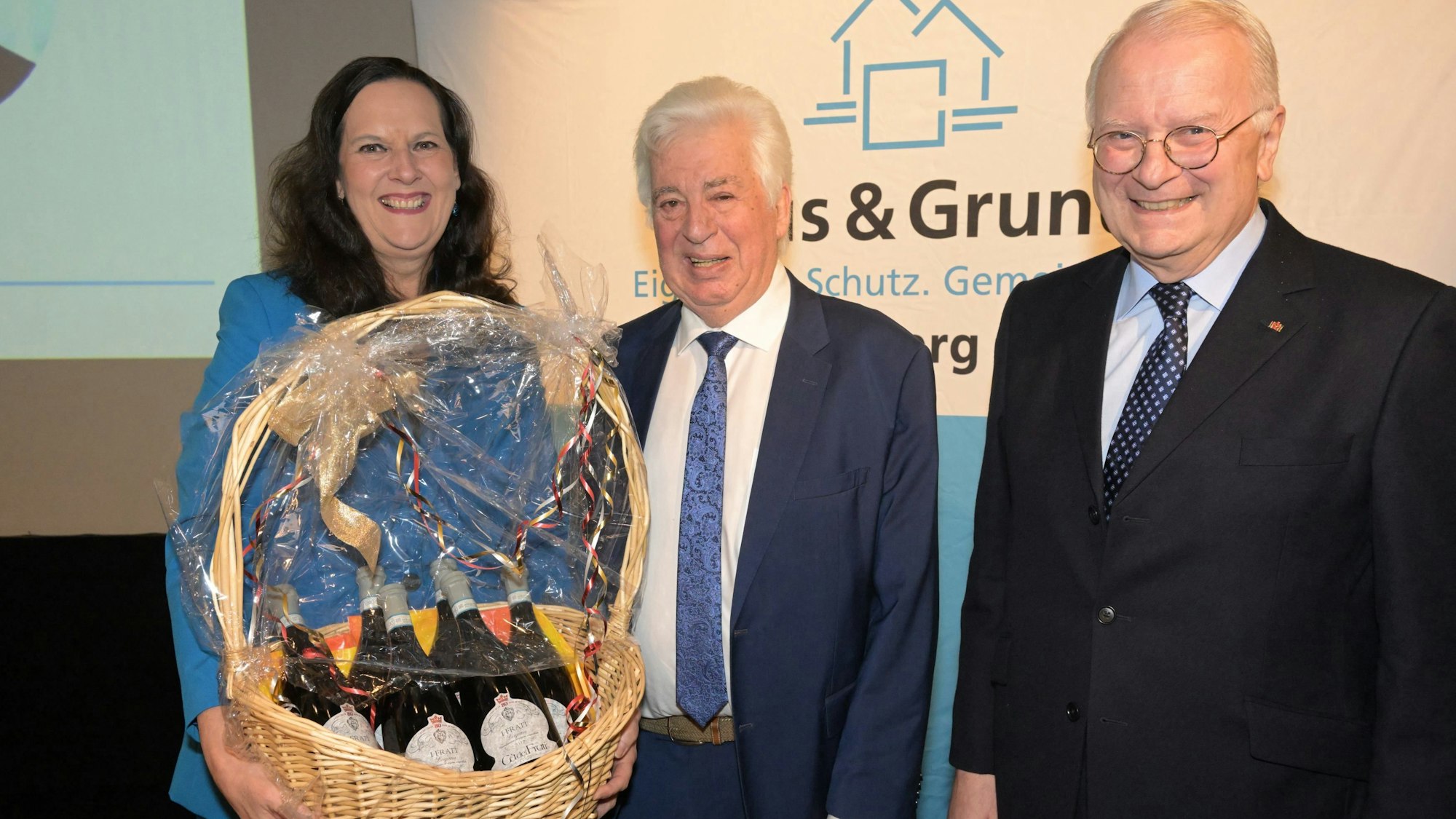 Der scheidende Vorsitzende von Haus & Grund Rhein-Berg, Peter Müller, steht zwischen Geschäftsführerin Sylvia Schönenbröcher mit Präsentkorb und Hubertus Prinz zu Sayn-Wittgenstein.