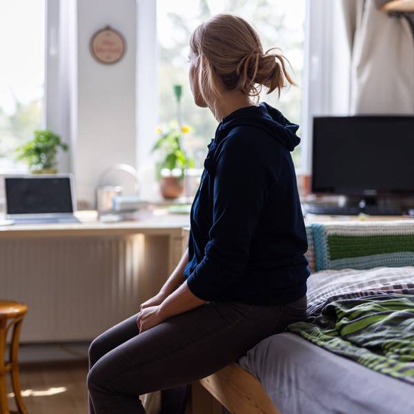ARCHIV - 13.08.2023, Niedersachsen, Hannover: ILLUSTRATION - Eine Studentin sitzt auf dem Bett in ihrem WG-Zimmer und schaut aus dem Fenster (gestellte Szene).