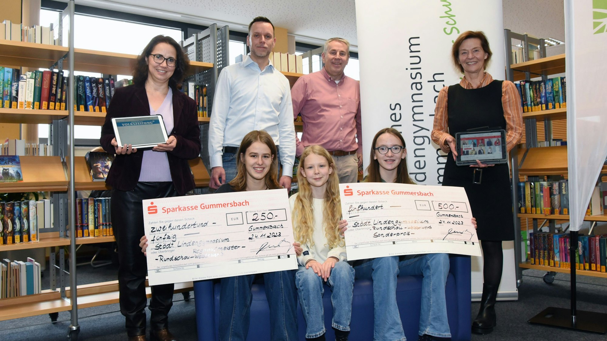 Die Schülerinnen halten die beiden großen Schecks in den Händen.
