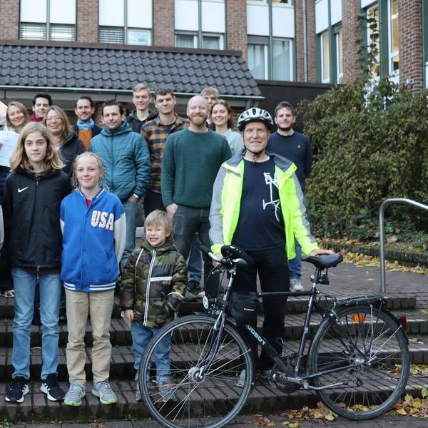 Eine Gruppe von Radfahrerinnen und Radfahrern mit einem Fahrrad auf den Stufen vor dem Rathaus.