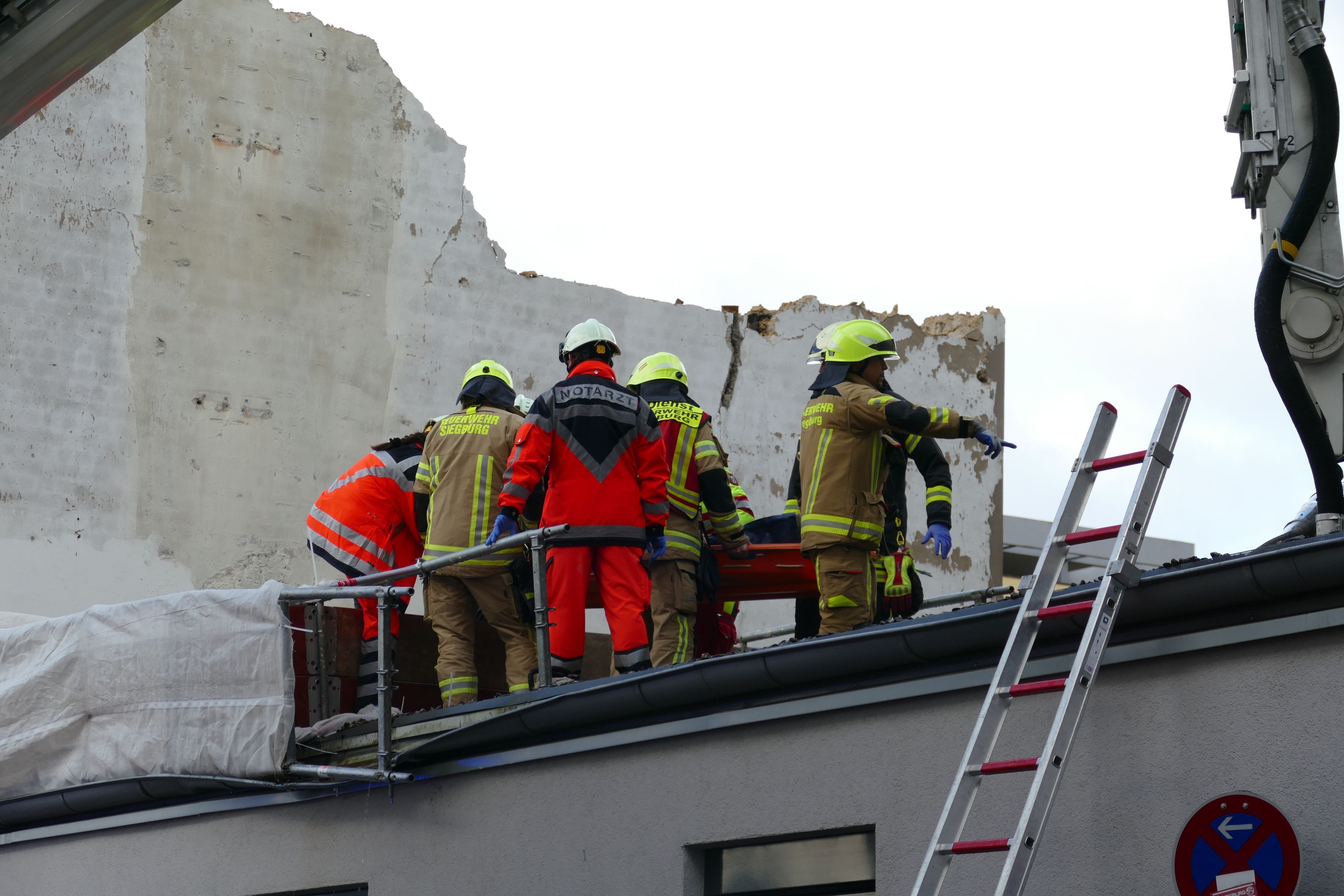 Rettungskräfte stehen auf einem Dach.