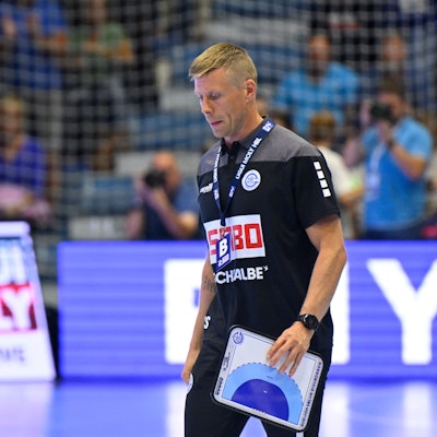 VfL-Trainer Gudjon Valur Sigurdsson läuft mit einer Zeigetafel über ein Handball-Spielfeld.