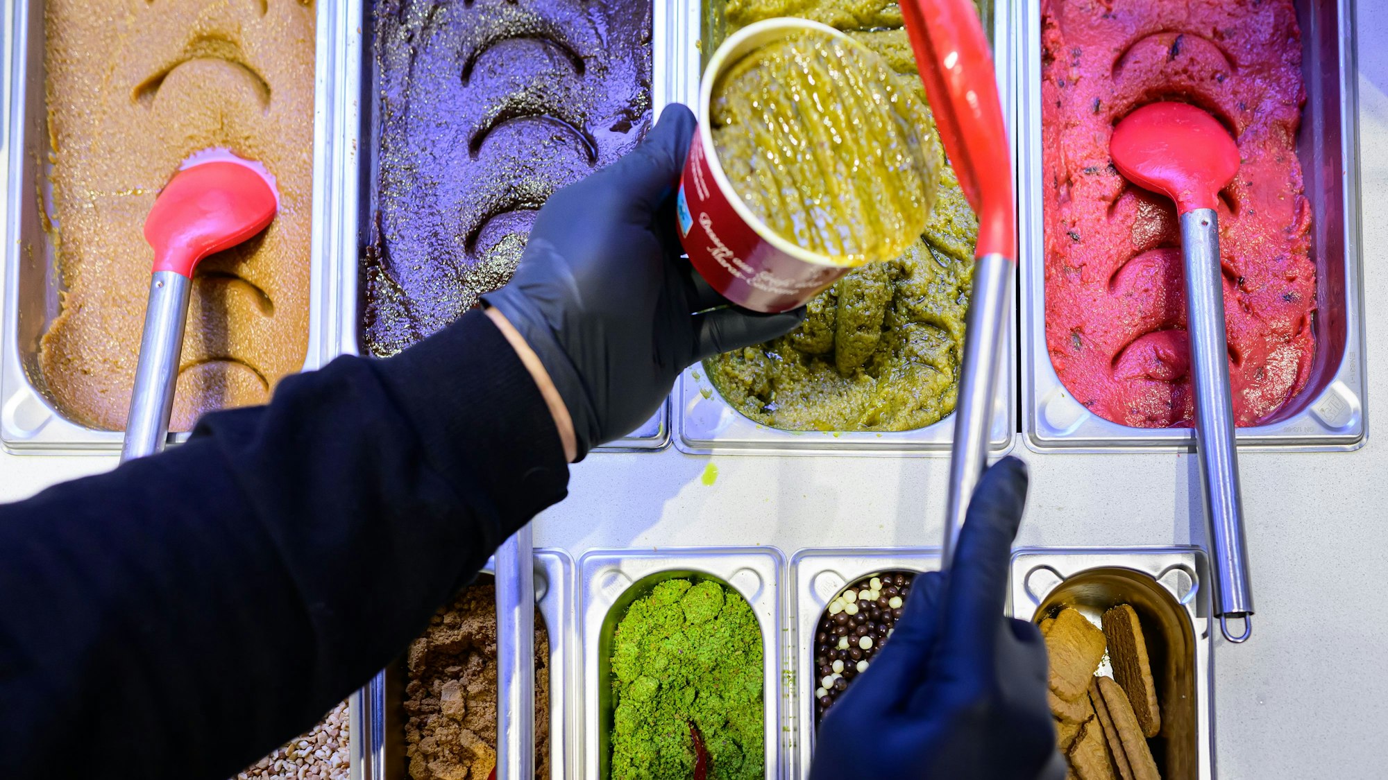 Bunte Metalleimer gefüllt mit Helva-Grieß und Toppings.