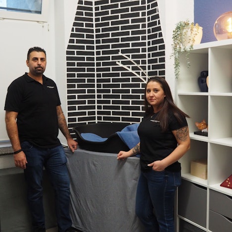 Zwei Personen stehen an einem Hundekörbchen.