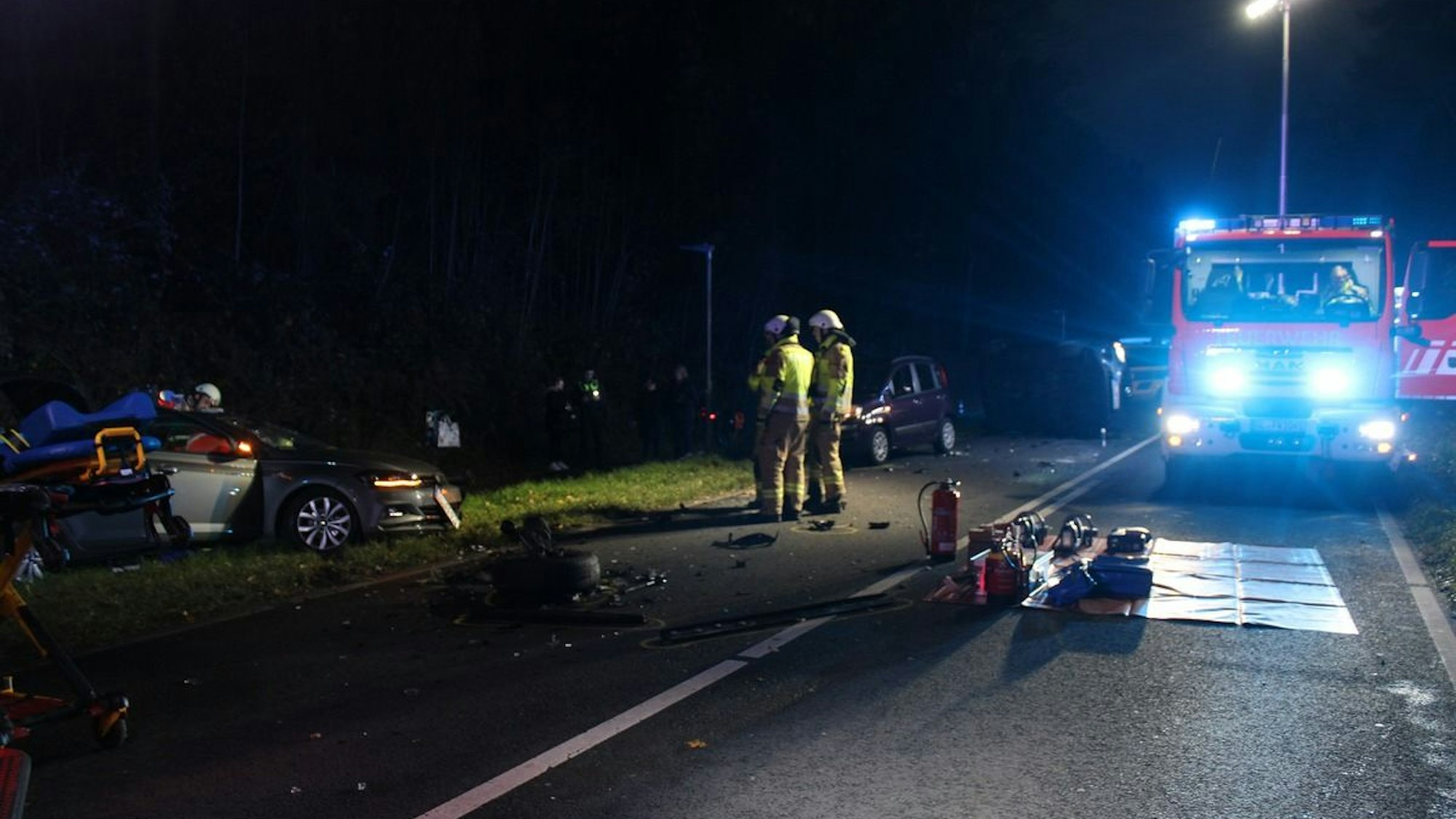 Einsatzkräfte am Unfallort, den die Feuerwehr ausleuchtet.