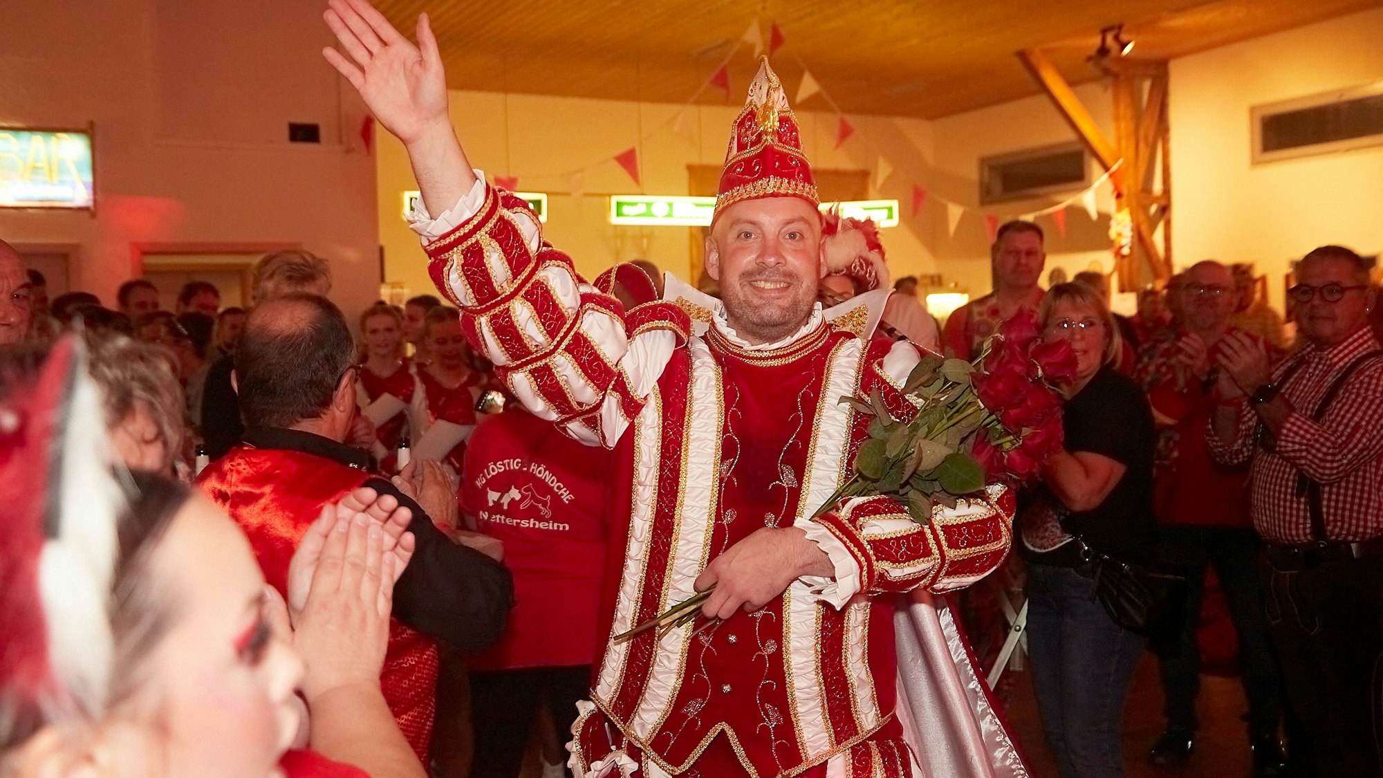 Das Bild zeigt Prinz Knibbi beim Einzug in den Dorfsaal. Er winkt in die Kamera.