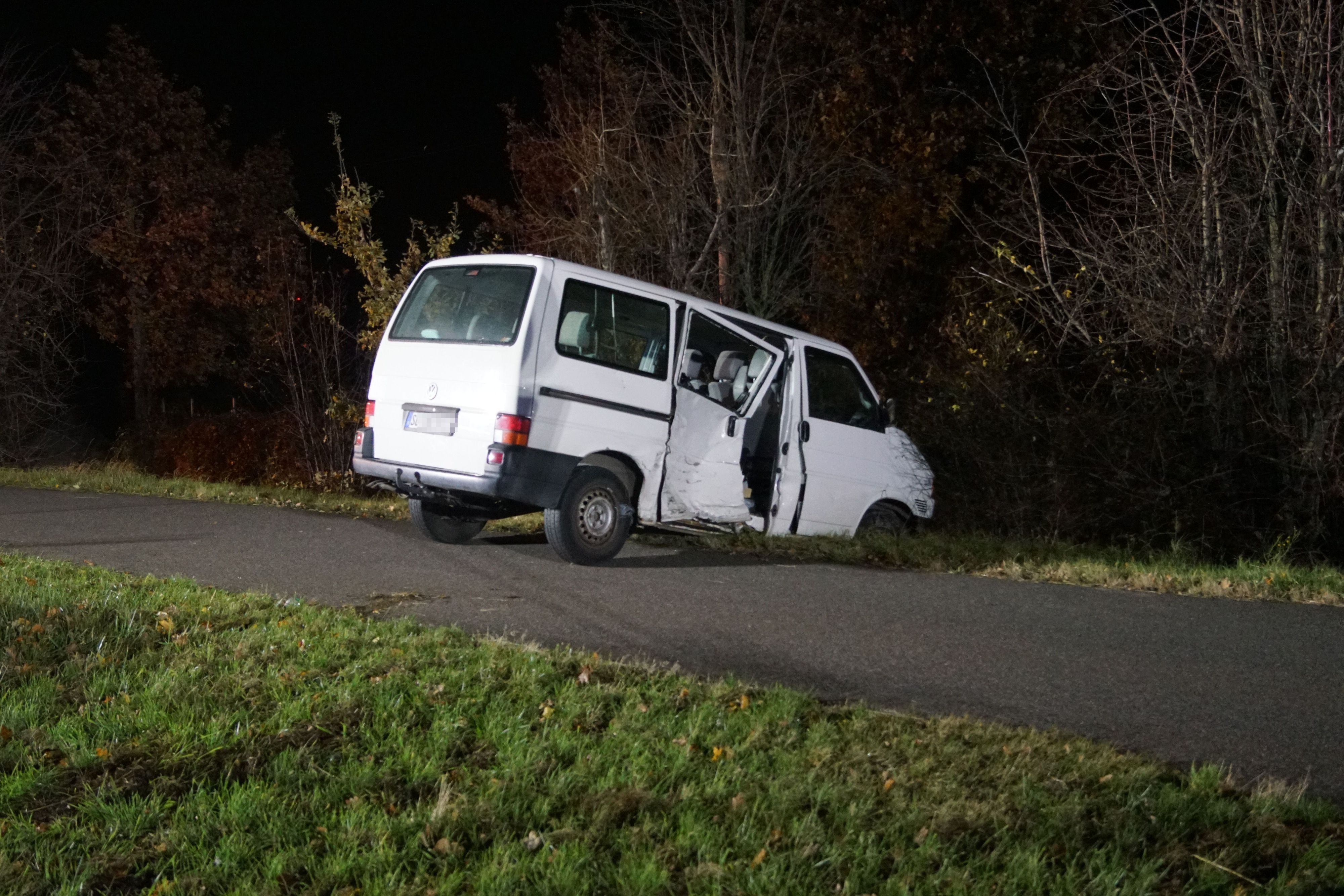 Das Bild zeigt einen weißen VW Bus, der bei der Kollision an der Beifahrerseite demoliert wurde.