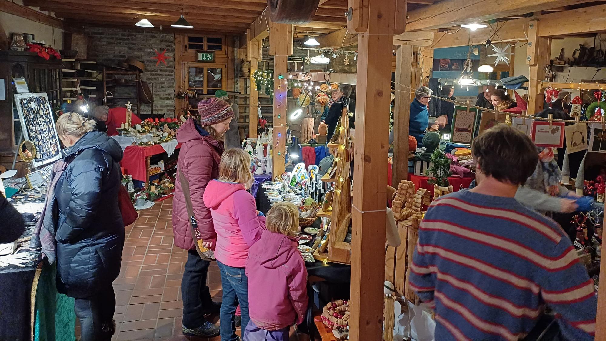 Besucher an bunt dekorierten Marktständen in der Mühle