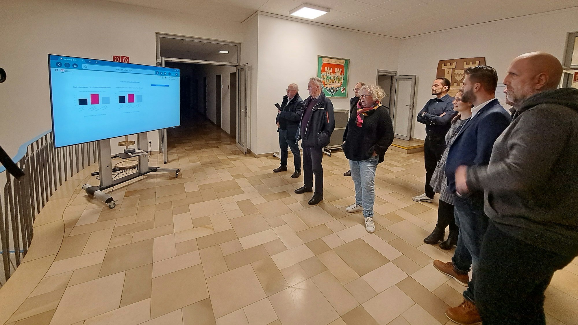 Mehrere Menschen gucken auf einen Bildschirm.