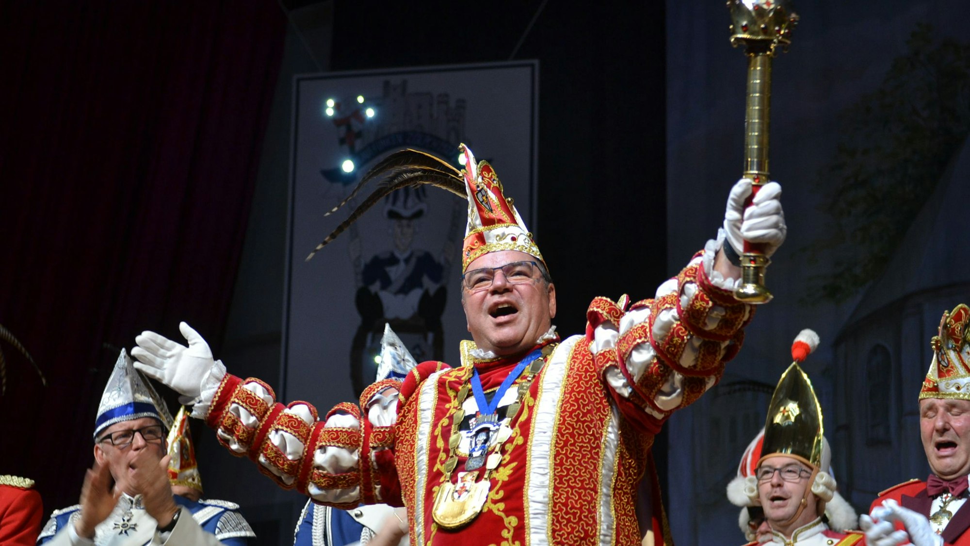 Prinz Ralf I. steht im Ornat auf einer Bühne und hält das Zepter in die Höhe.