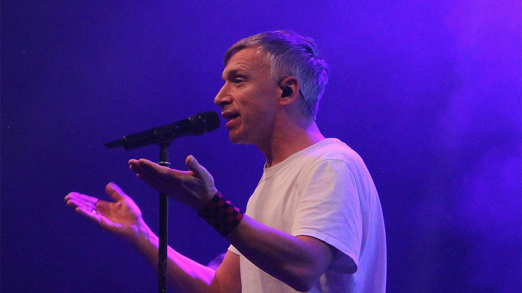 Der Frontman der kölschen Band Kasalla, Bastian Kampmann, steht vor einem Mikrofon und singt.