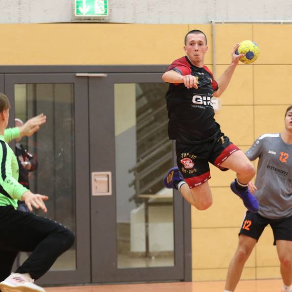 Palmersheims Timo Johnen steigt mit dem Ball in der Hand zum Sprung hoch. Ein Gegenspieler schaut zu, der Torwart hält eine Hand hoch.