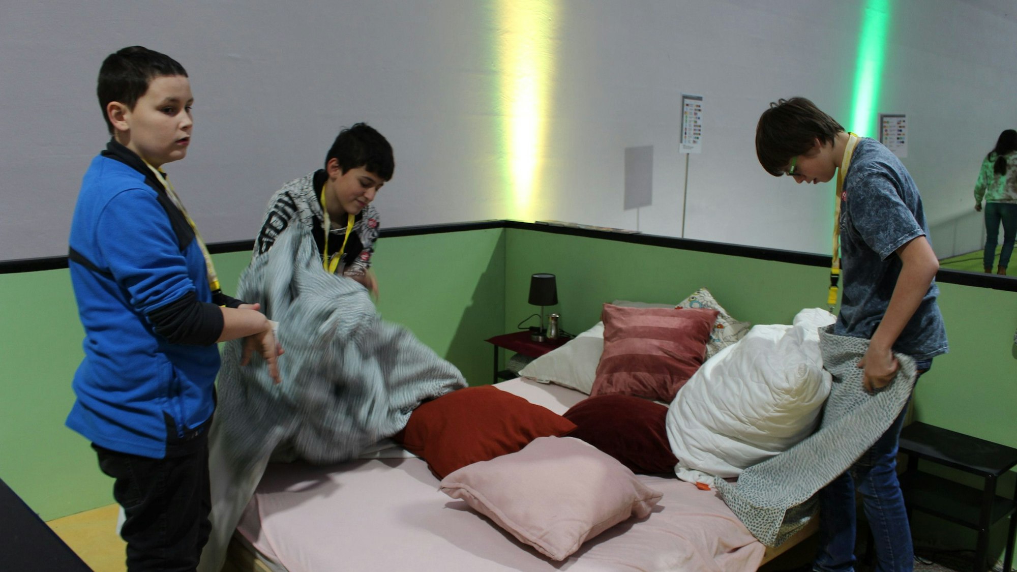 Drei Jungen beziehen ein Bett.