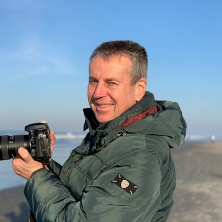 Wolfgang Abegg im Porträt. Er hält eine Kamera in der Hand.