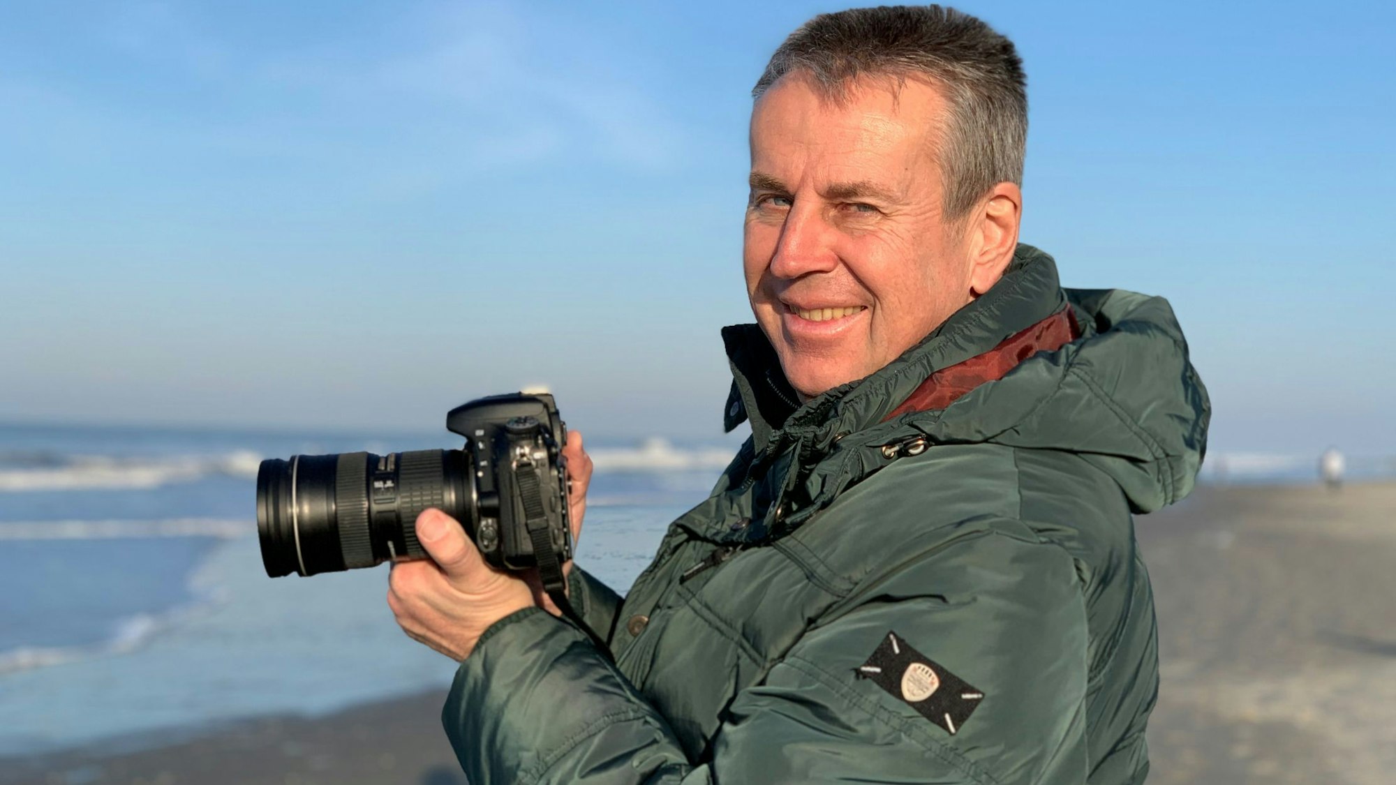 Wolfgang Abegg im Porträt. Er hält eine Kamera in der Hand.