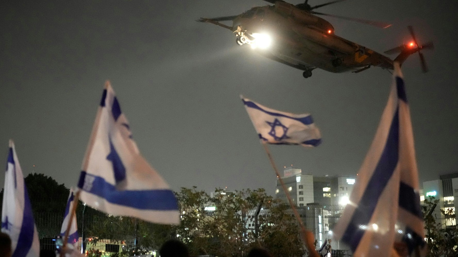 Menschen schwenkten am Sonntag israelische Fahnen, als ein Hubschrauber mit Geiseln, die von der Hamas aus dem Gazastreifen frei gelassen wurden, auf dem Hubschrauberlandeplatz des Schneider Children's Medical Center landete.