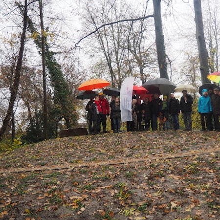 Eine Gruppe Menschen steht auf einem Hügel, auf den ein spiralförmig gewundener Weg führt.