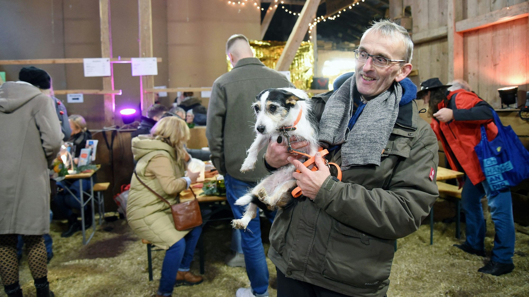 Ein Mann hält bei einem fest in einer Scheune einen Hund auf den Armen.